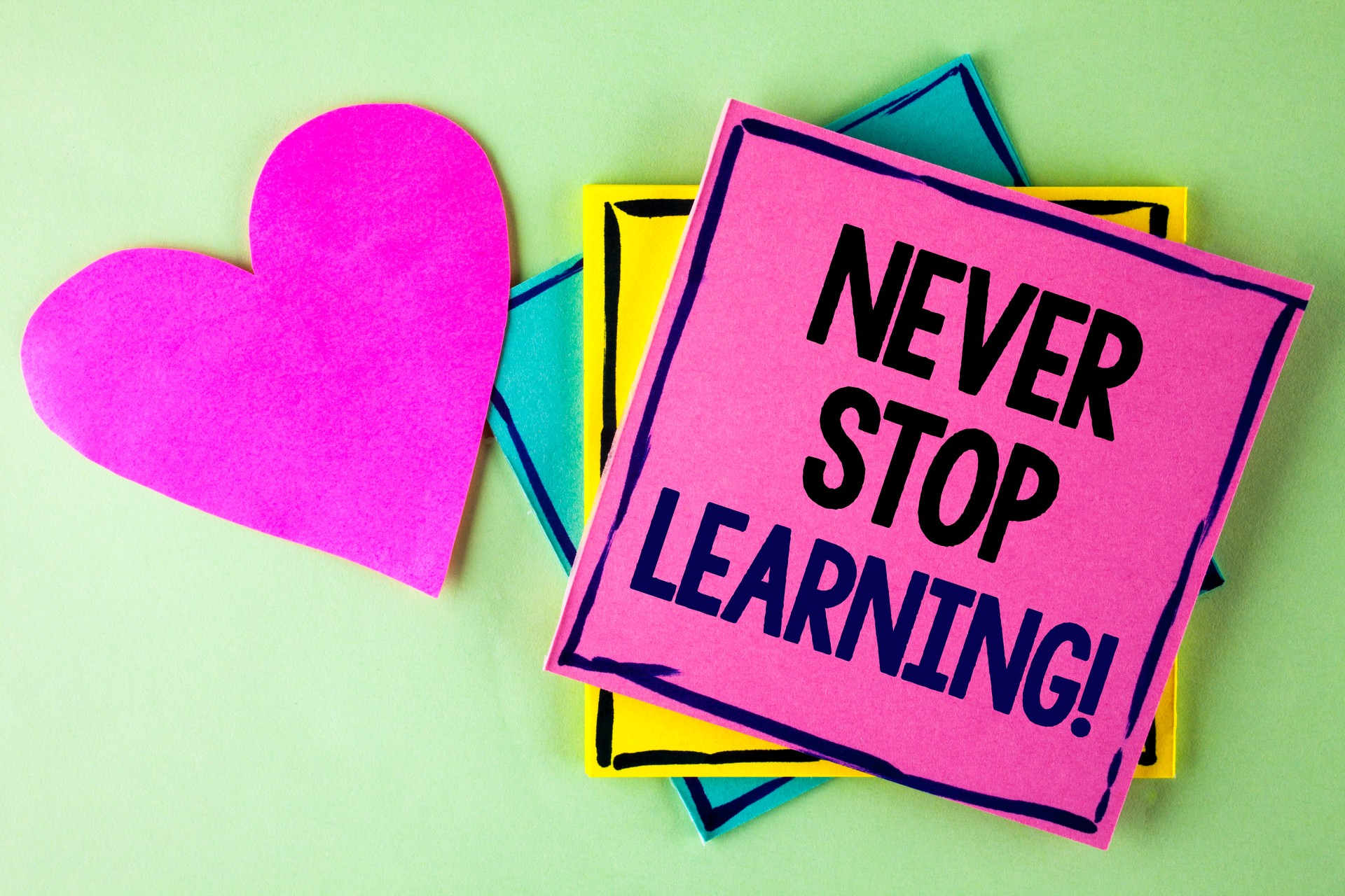 Writing note showing  Never Stop Learning Motivational Call. Business photo showcasing Keep educating yourself Improve Skills written on Pink Sticky Note Paper on plain background Heart next to it.